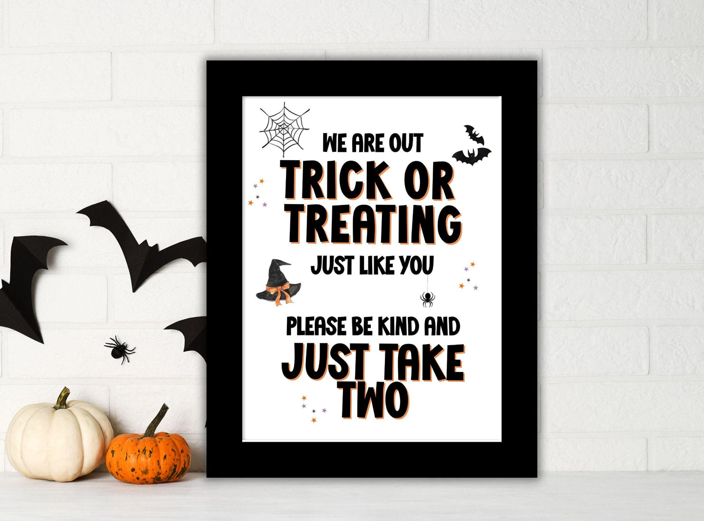 Framed Halloween-themed print with text and decorative elements on a white wall.
