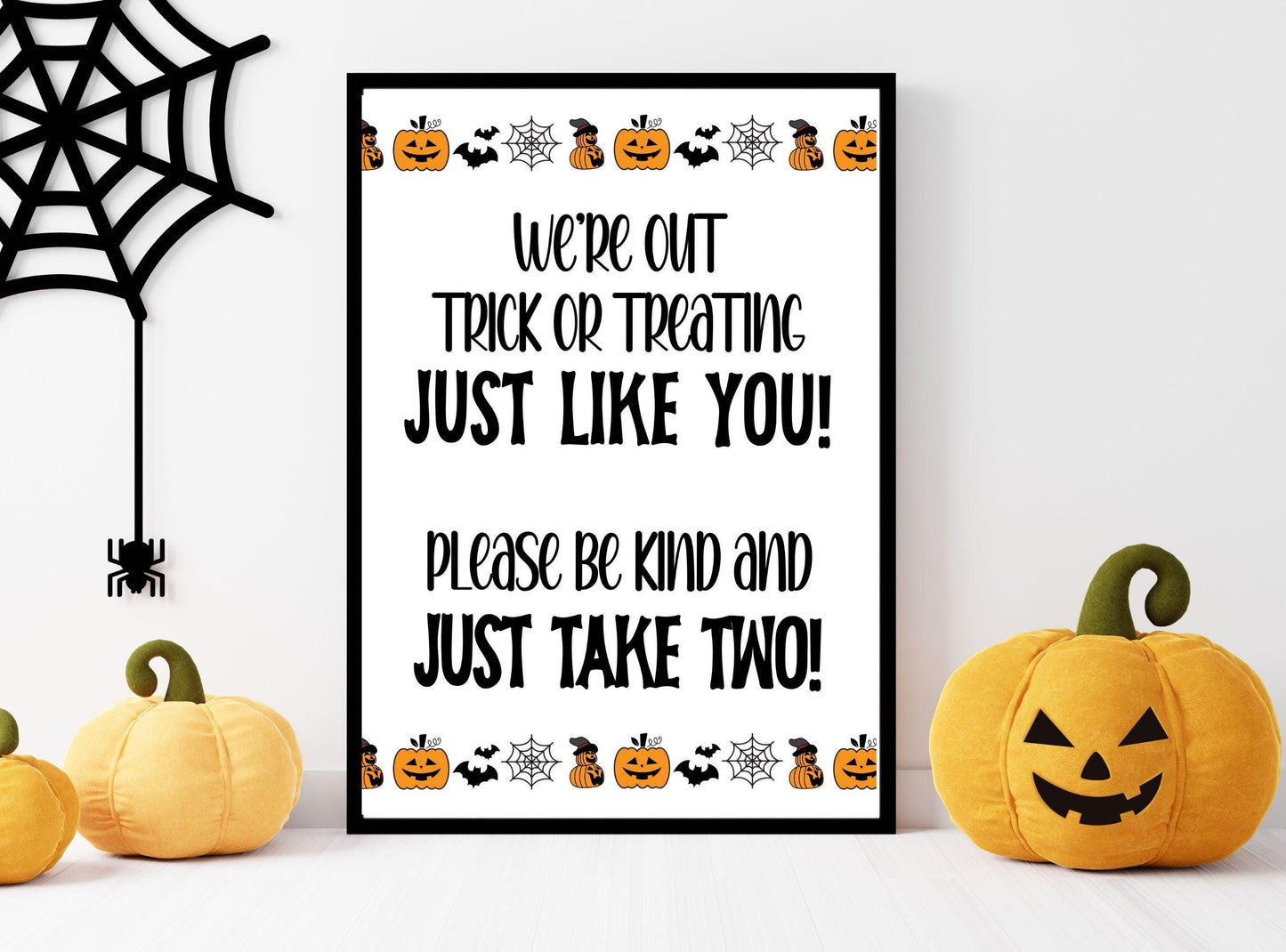Halloween-themed sign with pumpkins and spider web on a white background