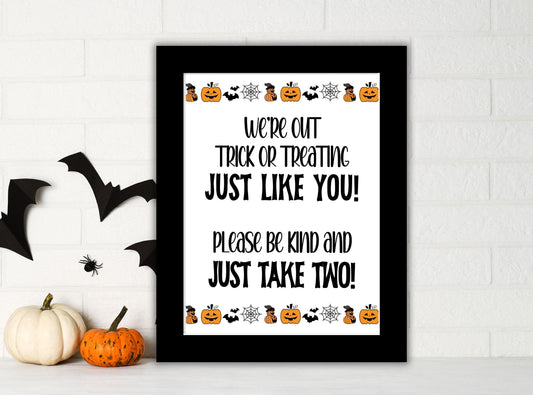 Halloween-themed sign with pumpkins and bats on a white wall.